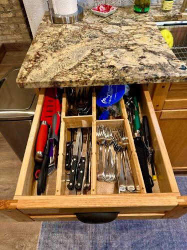 a wooden drawer full of utensils sitting under a counter at Be Still & Know, Fireplace, Firetable, Walk to Port in Port Washington