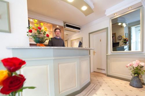 a man standing behind a counter in a room with flowers at Kocks Hotel Garni in Hamburg