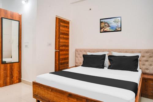 a bedroom with a large bed with a wooden headboard at Super Hotel O Neelbad Guest House in Bhopal