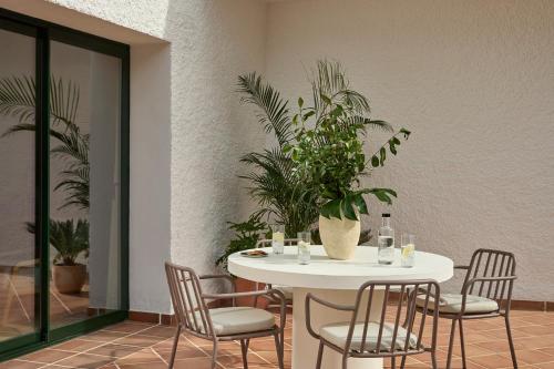 a white table with chairs and a potted plant at Kimpton Los Monteros Marbella by IHG in Marbella