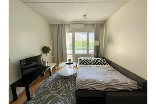a bedroom with a bed and a flat screen tv at Kotikaksio Grigio in Lahti