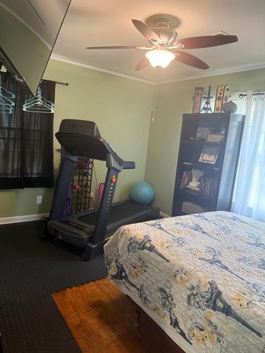 a bedroom with a treadmill and a bed and a ceiling fan at Duplex style home-quiet area in Warner Robins
