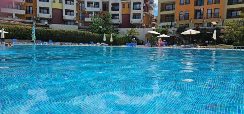 a large blue swimming pool with chairs and umbrellas at Apartament Sorrento in Marina Cape in Aheloy