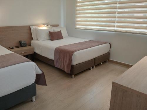 a hotel room with two beds and a window at Hotel Lomas 10 Medellin in Medellín