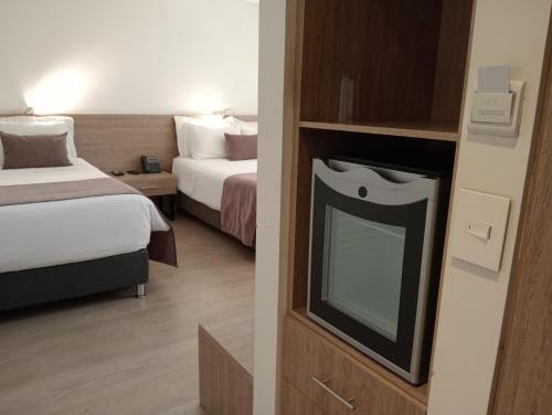 a hotel room with two beds and a tv at Hotel Lomas 10 Medellin in Medellín
