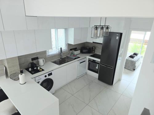 a kitchen with a black refrigerator and white cabinets at Villa Amavi Peyia in Peyia