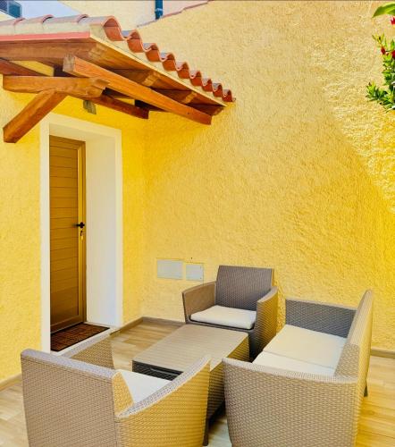 a patio with chairs and tables and a yellow wall at CASA SACURI in Rudalza