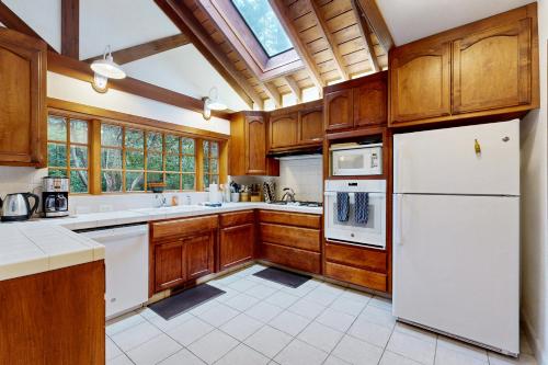 a kitchen with wooden cabinets and a white refrigerator at Little River Redwoods in Little River