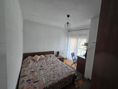 Marina G apartment في بريشتيني: غرفة نوم بها سرير ومكتب ونافذة