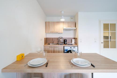 - une cuisine avec une table en bois, des assiettes et des verres à vin dans l'établissement Cozy 2P Port de Nice garage, à Nice