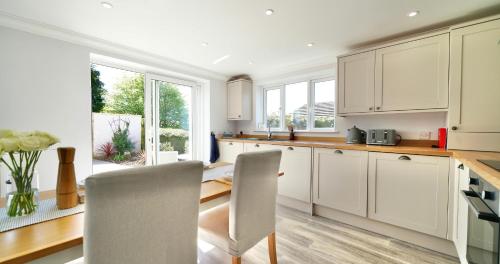 a kitchen with white cabinets and a table and chairs at Joannes Retreat, Dog Friendly Property in Weymouth with Free Parking in Weymouth