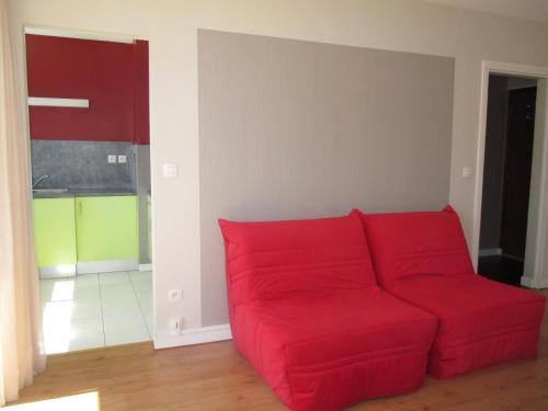 a red couch sitting in a living room at Grand studio lumineux ,centre ville, grande plage,Quiberon IZE1UU in Quiberon