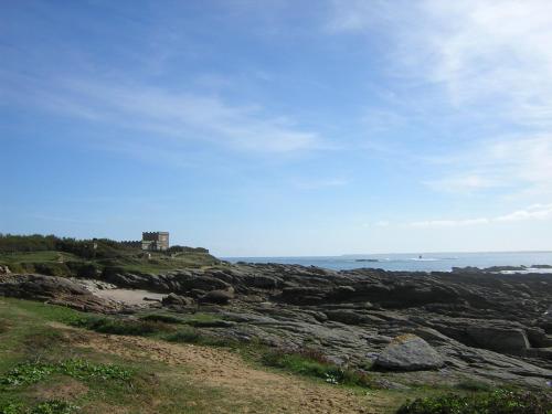 a view of a rocky beach with a house in the background at Grand studio lumineux ,centre ville, grande plage,Quiberon IZE1UU in Quiberon