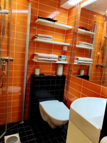 an orange bathroom with a toilet and a shower at Spacious and bright 2 bedroom apartment in Oulu
