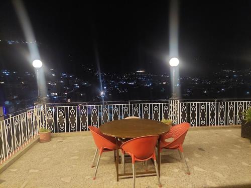 a table and chairs on a balcony at night at Shalimar Hotel in Muzaffarabad