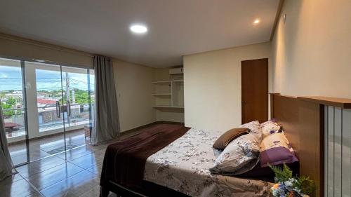 a bedroom with a bed and a large window at 4 quartos, sendo 2 suítes - uma com varanda privativa, a 700m da Praia da Boca da Barra e 2,5km da orla de Tamandaré, Wifi 200MB e cozinha completa - Piscina e estacionamento privativos - Ideal para grupos e famílias - tranquilo para home office in Tamandaré