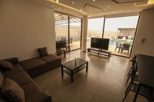 a living room with a couch and a tv at Yaras villa in Ash Shāghūr