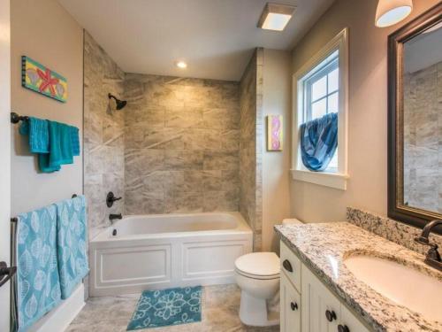a bathroom with a tub and a toilet and a sink at Garden Cottage 08 in Jekyll Island