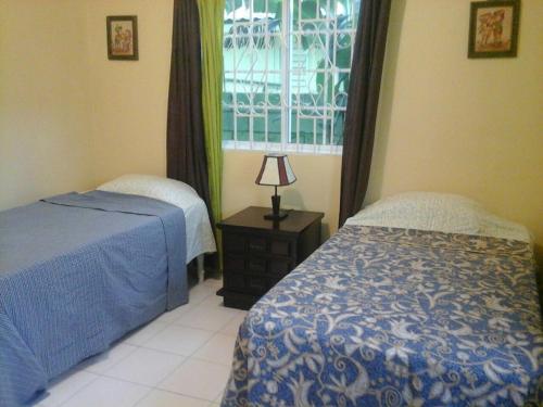 1 dormitorio con 2 camas y ventana en Relax in Sunny Montego Bay, Jamaica, en Montego Bay