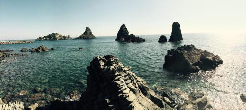 a group of large rocks in the water at La Scivola Rooms in Acitrezza