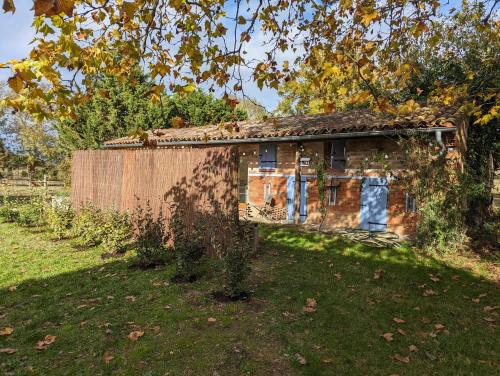 an old brick house with a fence in a yard at Dépendance avec balnéothérapie in Maurens