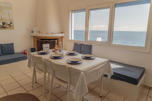 a dining room with a table with chairs and a fireplace at Infinity Blue Villas, Kythnos in Kithnos