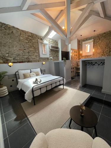 a bedroom with a large bed and a stone wall at La Tuilerie du Bazalac in Trèbes