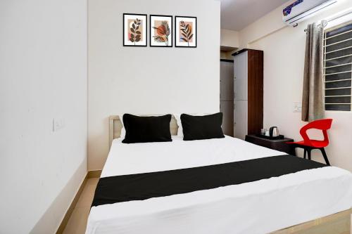 a bedroom with a white bed and a red chair at Hotel O Om Sai Residency in Bengaluru