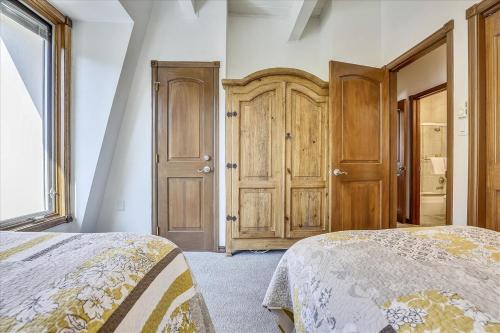 a bedroom with two beds and wooden doors at Lovely Aspen Condo with Mountain Views & Hot Tub in Aspen