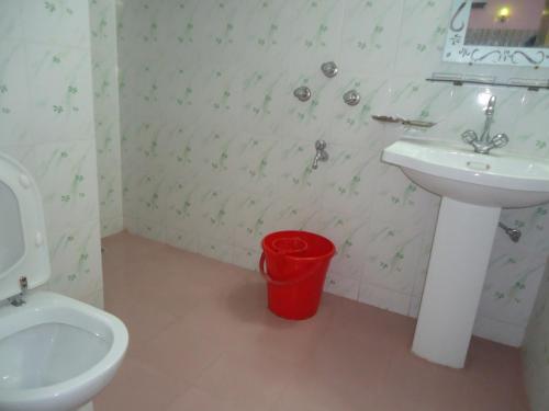 a bathroom with a sink and a toilet and a bucket at Unity Inn in Cox's Bazar