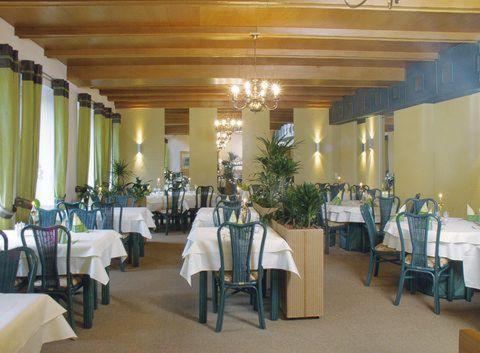 uma sala de jantar com mesas e cadeiras brancas e um lustre em Hotel Hansen em Heinsberg