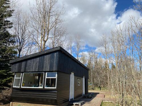 una pequeña casa negra sentada en una terraza de madera en The Tiny House, en Laugaras
