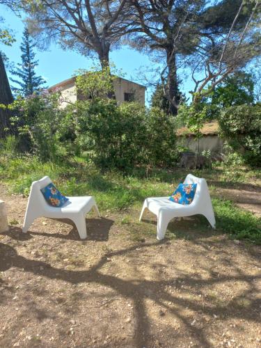 a couple of white chairs sitting in the grass at Un cabanon en Provence in Auriol