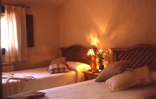 um quarto com duas camas e um candeeiro sobre uma mesa em Casa Rural Nelia em Villalba de la Sierra