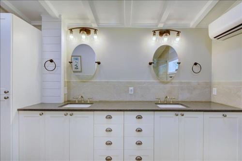 ein Badezimmer mit zwei Waschbecken und zwei Spiegeln in der Unterkunft Beachcomber Cottage in Jekyll Island