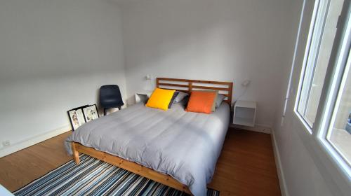 a bedroom with a bed with orange and yellow pillows at Le Haras Ouest in Libourne