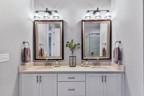 a bathroom with two sinks and two mirrors at Moorings 104 in Jekyll Island