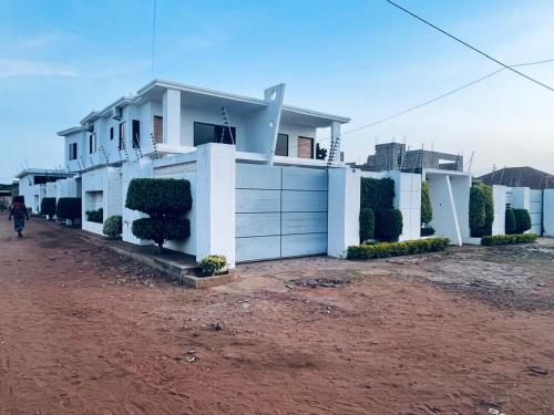 a white house with a red dirt road in front of it at Villa esperança in Fombeni
