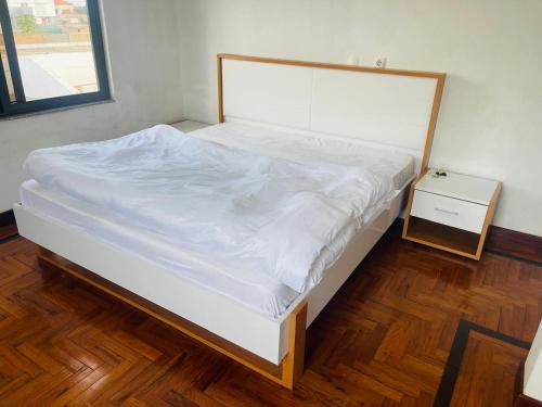 a bedroom with a bed with white sheets and a night stand at Villa esperança in Fombeni