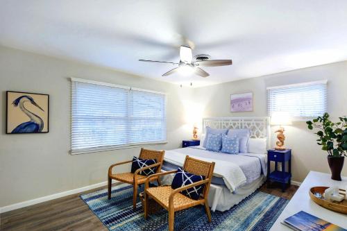 ein Schlafzimmer mit einem Bett und zwei Stühlen und einem Deckenventilator in der Unterkunft A Wave From It All in Jekyll Island