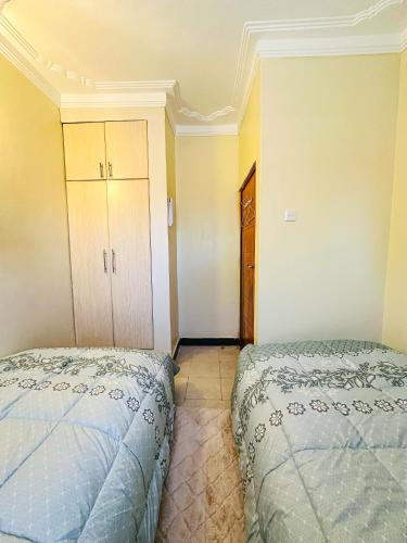 a bedroom with two beds and a closet at Comfort homes BnB in Kampala