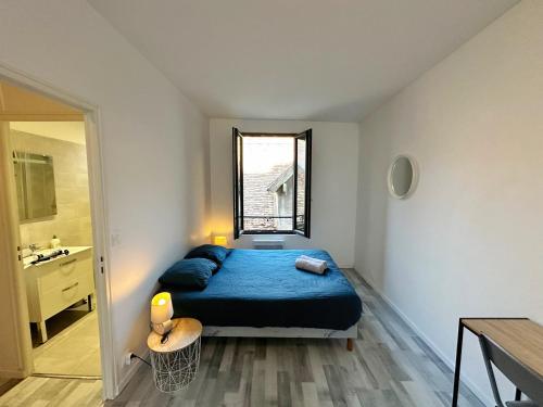 a bedroom with a blue bed and a bathroom at L'Évasion en Bord de Seine in Bray-sur-Seine