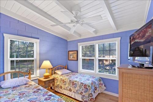 a blue bedroom with two beds and a ceiling fan at At Twelve Oaks in Jekyll Island