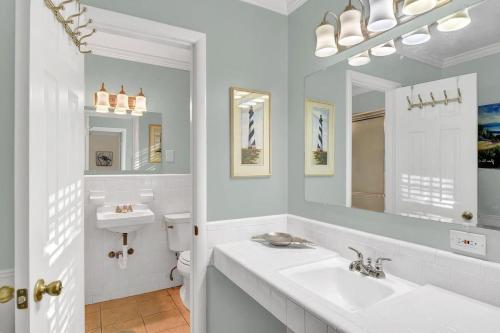 a white bathroom with a sink and a mirror at Newbern Cottage in Jekyll Island