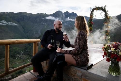 a man and woman sitting on a ledge drinking wine at Stardome Spiritual Experience in Ollantaytambo