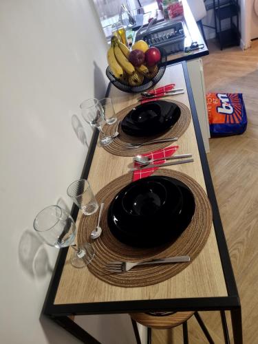 - une table avec des assiettes, des verres et un bol de fruits dans l'établissement Golden Cottage, à Villeneuve d'Ascq