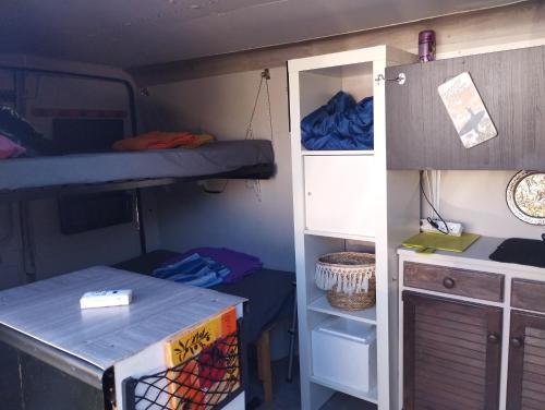 Cette petite chambre comprend des lits superposés et un bureau. dans l'établissement Van aménagé 3 couchages sans SANITAIRE proche de la plage, à Mauguio