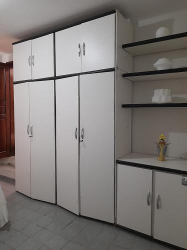 a white kitchen with white cabinets and shelves at Pousada Marília Rodrigues in Piranhas