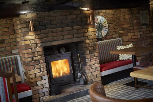 a brick fireplace with a fire in it at The Ingram Arms in Laughton