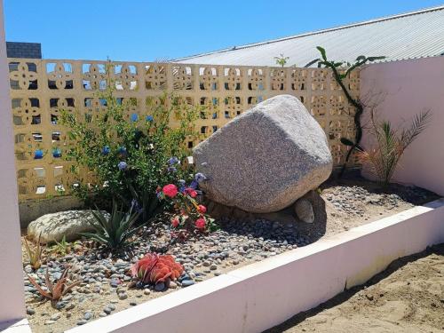 a garden with a rock and flowers in front of a fence at Casa Bonita in El Pescadero